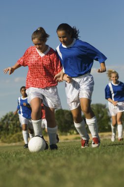 Genç kızlar futbol oynuyor.