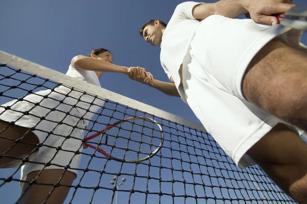 Estrechar las manos sobre la red de tenis — Foto de Stock