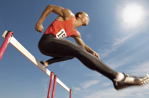 Athlete jumping over a hurdles