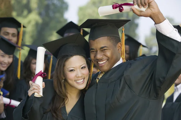 Graduates hoisting diplomas — Stock Photo, Image