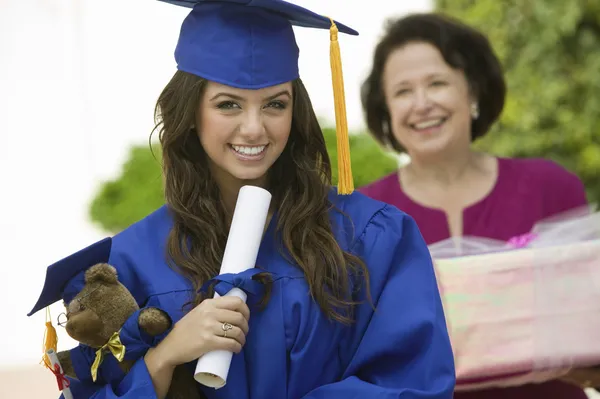 Graduate holding teddy bear and diploma — Stock Photo, Image