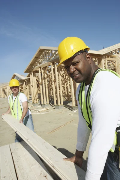 Travailleurs de la construction empilant du bois — Photo