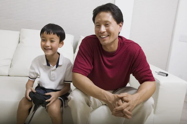 Padre viendo hijo jugar videojuego — Foto de Stock