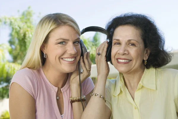 Matka i córka dzielenie słuchawki — Zdjęcie stockowe