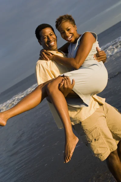 Mann trägt Frau auf See — Stockfoto