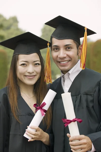 Two graduates holding diplomas — Stock Photo, Image