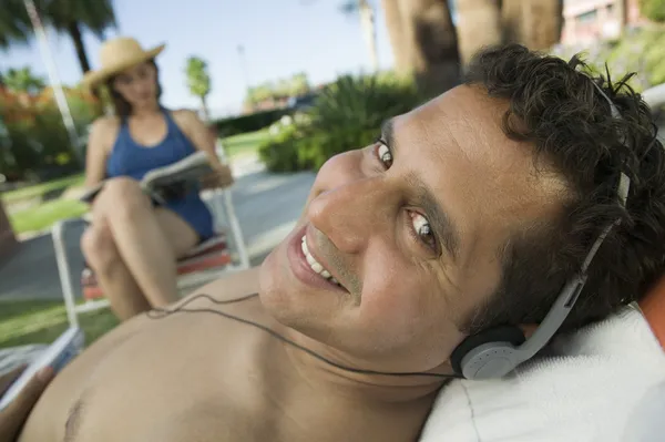 Hombre acostado en una tumbona escuchando auriculares — Foto de Stock