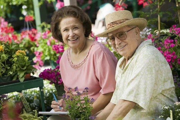 Äldre par sitter bland blommor — Stockfoto