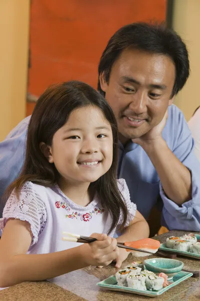 Padre guardando figlia mangiare sushi — Foto Stock