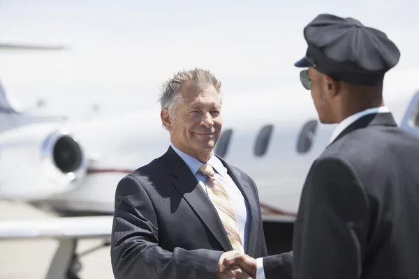 Businessman shaking hands with pilot — Stock Photo, Image