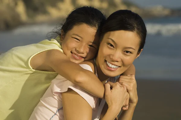 Primer plano retrato de la joven mujer piggybacking hija en la playa — Foto de Stock