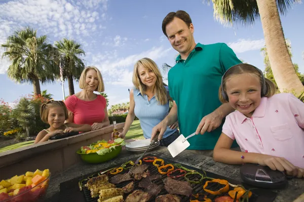 Girl listening to music player at outdoor barbecue — Stock Photo, Image