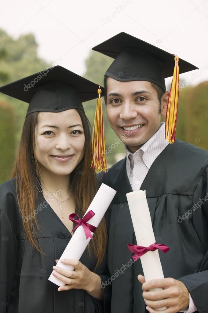 Two graduates holding diplomas