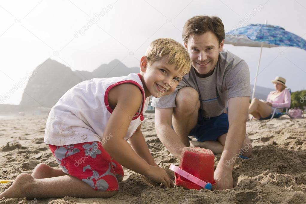 Father building sandcastle with son