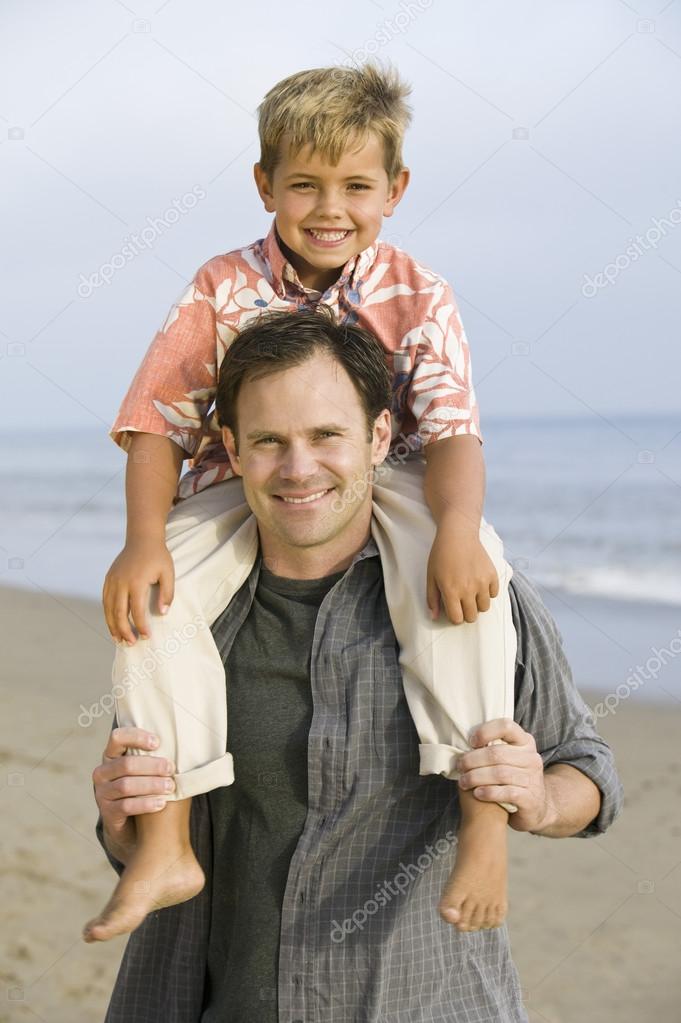 Boy on fathers shoulders at beach