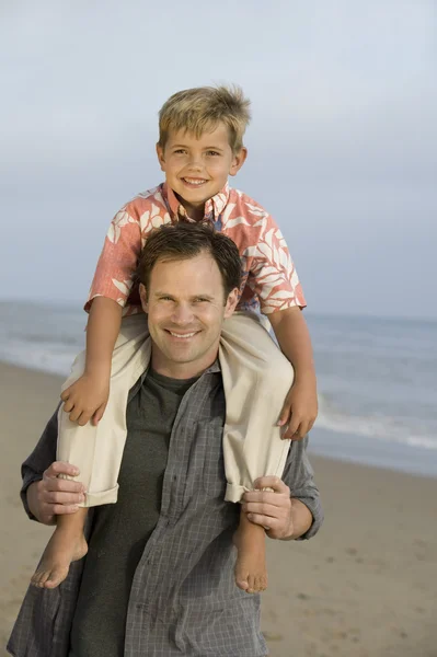 Отец с сыном на плечах на пляже — стоковое фото