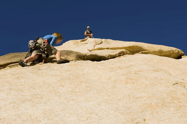 Uomo che assiste la donna arrampicata — Foto Stock