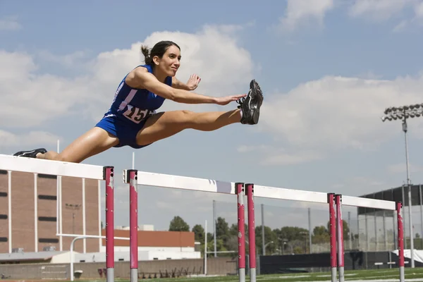 Female athlete jumping over a hurdles — Stock Photo, Image