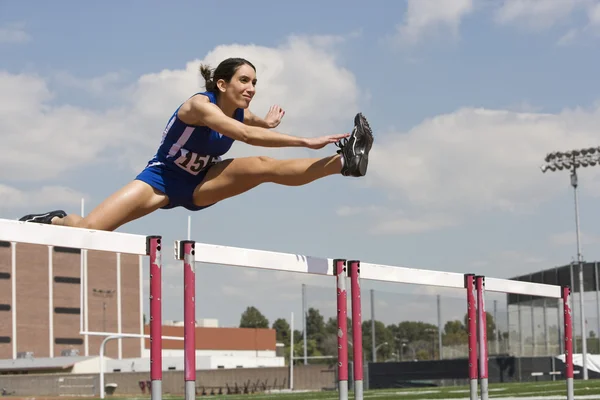 Athlète féminine sautant par-dessus un obstacle — Photo