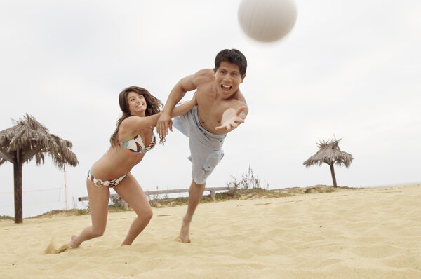 Woman Holding Man Back from Diving for Volleyball