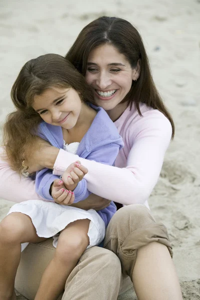 Moeder omhelst dochter op strand — Stockfoto