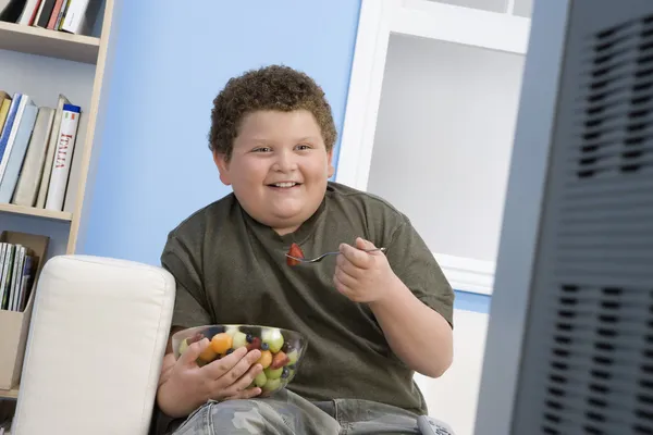 Övervikt pojken äta frukter — Stockfoto