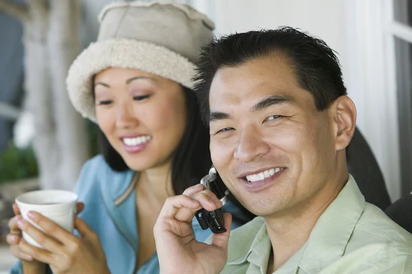 Uomo sul cellulare con donna che beve caffè — Foto Stock