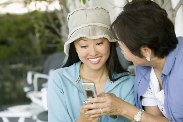 Mãe e filha usando telefone celular — Fotografia de Stock