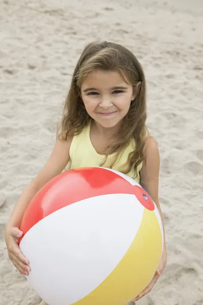 Chica sosteniendo pelota de playa en la playa — Foto de Stock