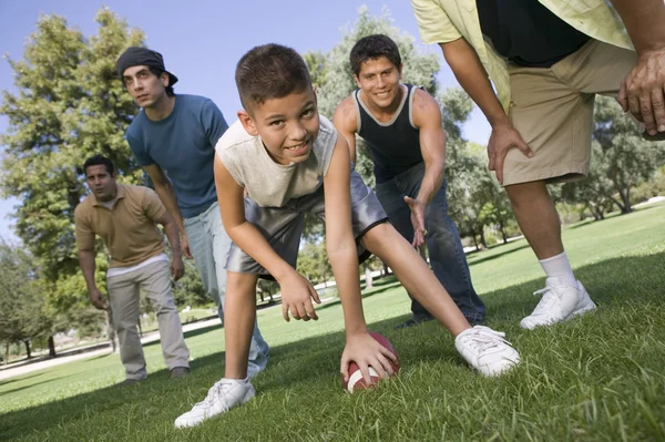 Garçon jouer au football avec un groupe d'hommes . — Photo