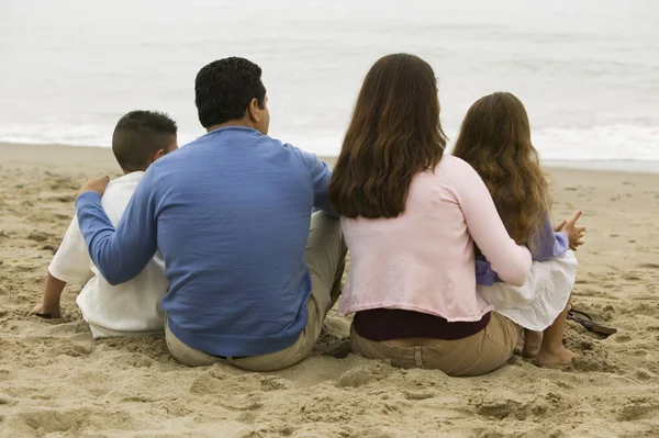 Familia sentada en la playa — Foto de Stock