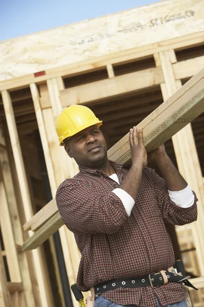 Travailleur de la construction transportant du bois — Photo