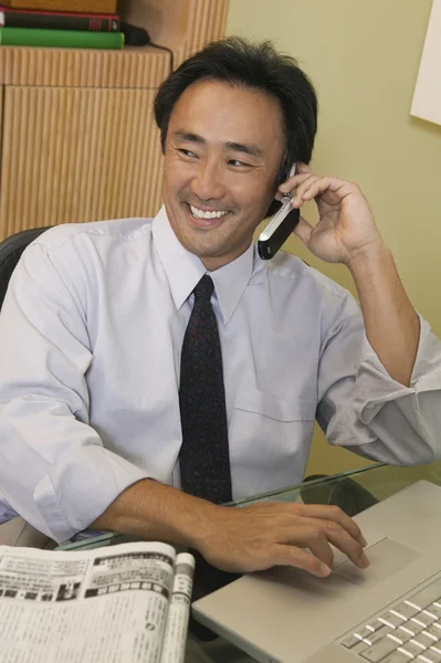 Empresario que usa teléfono celular y computadora portátil — Foto de Stock