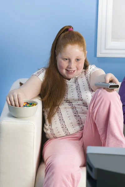 Chica con sobrepeso come comida dulce en el sofá —  Fotos de Stock