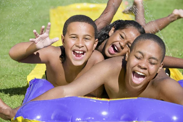 Children sliding on water slide — Stock Photo, Image