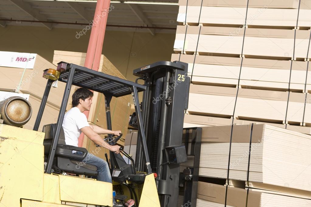 Male laborer with forklift stacking wood