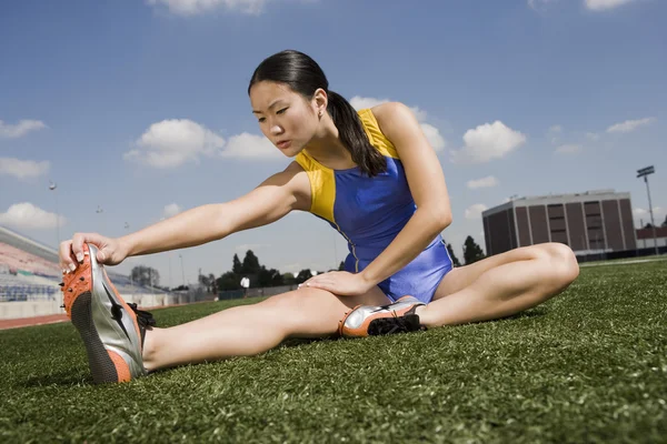 Athlete stretching on the field — Stock Photo, Image