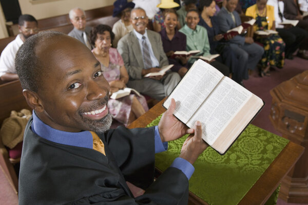 Проповедник у алтаря держит открытую Библию
