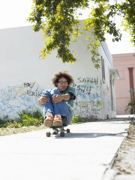 Mann sitzt auf Skateboard — Stockfoto