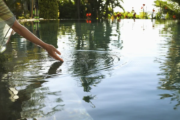 Frau streckt Hand aus, um See zu berühren — Stockfoto