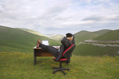 Businessman relaxing in mountain clipart