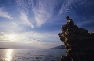 Man sitting on rock overlooking ocean