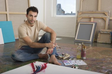 Male artist sitting with painting tools clipart