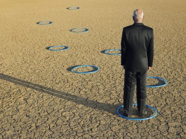 Businessman standing in hoops in desert clipart