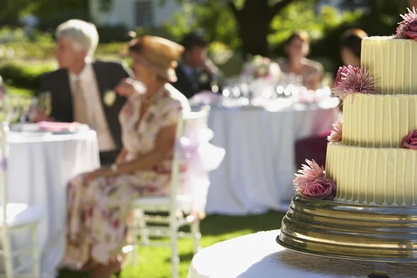 Düğün pastası masalarda oturan misafirler ile — Stok fotoğraf