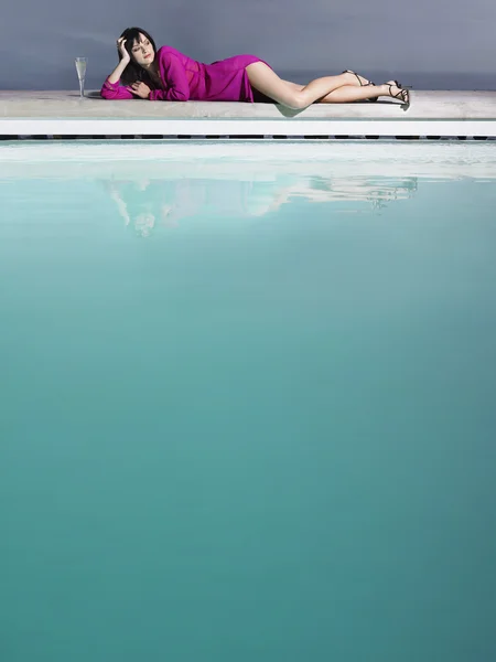 Mujer reclinada junto a la piscina — Foto de Stock