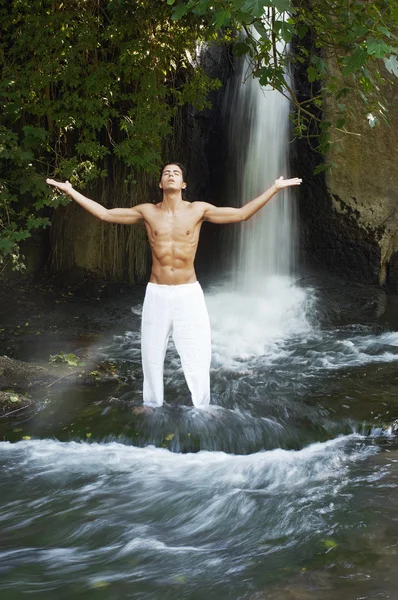 Человек медитирует у водопада — стоковое фото