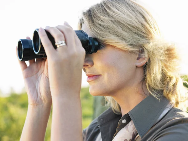 Frau blickt durch Fernglas — Stockfoto