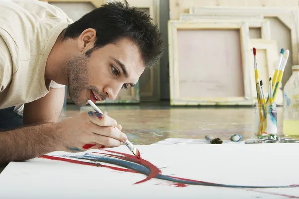 Homem pintando sobre tela no chão do estúdio — Fotografia de Stock