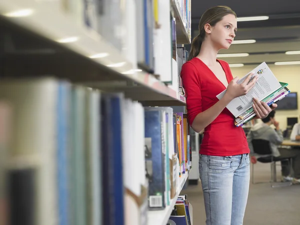 Studente che legge libri di testo in biblioteca — Foto Stock